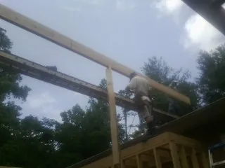 Carpenter setting a ridge beam over a new addition frame — Ice Dam Removal by Roofing Brothers in Collinston