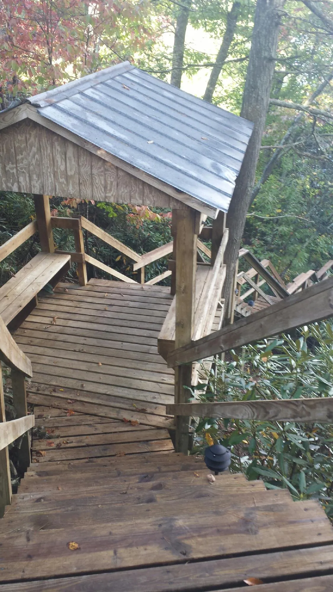 Metal roofed shelter over wooden steps on a wooded walkway — Skylight Repair & Installation work by our crew in Collinston