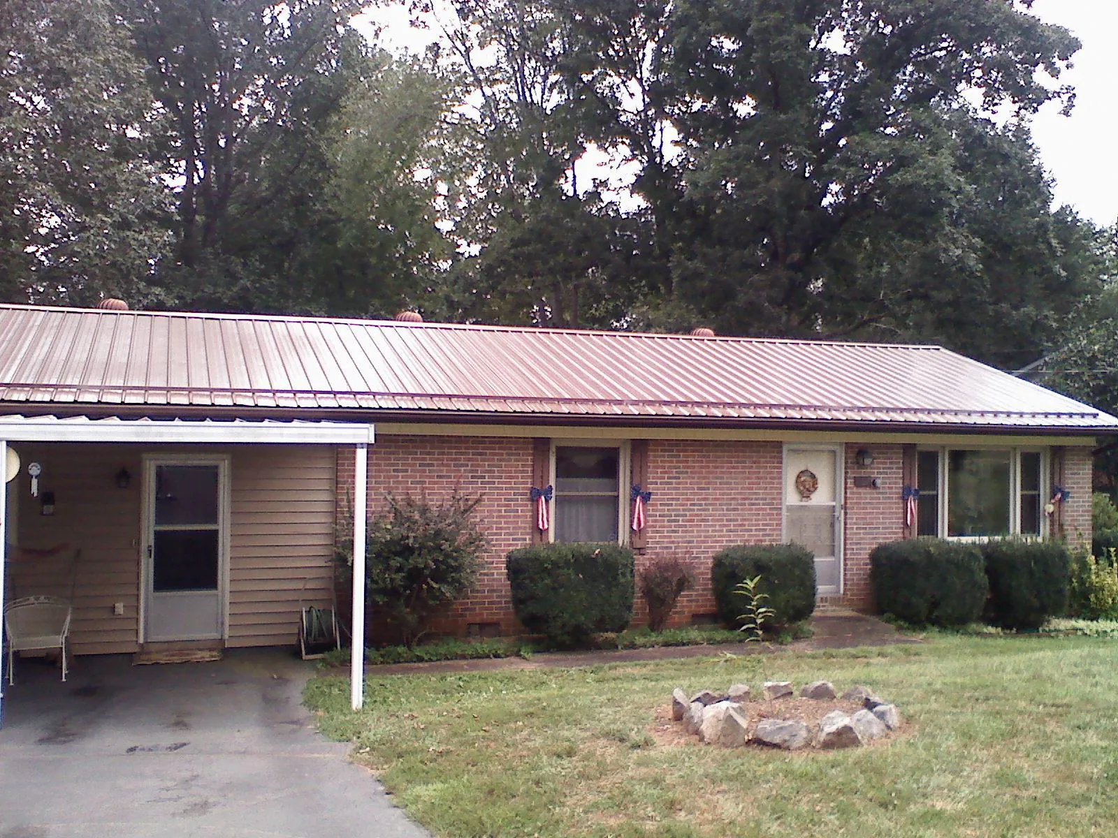 Bronze metal roof and carport on a brick ranch home — Roof Repair work by our crew in Collinston